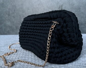 May include: Black crocheted handbag with a gold chain strap.