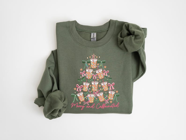May include: Olive green sweatshirt with a graphic of a Christmas tree made of coffee cups, bows, and stars. The text "Merry and Caffeinated" is printed in pink script at the bottom of the design. The sweatshirt has long sleeves.