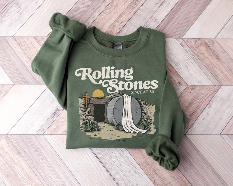 May include: Green sweatshirt with a graphic of a stone tomb with a white cloth draped over it. The text "Rolling Stones Since AD 33" is printed on the sweatshirt.