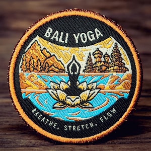 May include: Circular patch with a black border and orange stitching. The patch features the words "Bali Yoga" above an illustration of a person in a yoga pose on a lotus flower. The words "Breathe, Stretch, Flow" are below the illustration.