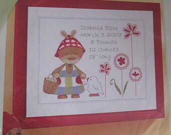May include: A cross-stitch embroidery design featuring a bunny holding a basket of flowers. The design includes the text "Isabelle Rose, March 3, 2007, 8 Pounds, 12 Ounces, 18" Long" and the words "Lapin câlin" and "Conejito cariñoso".