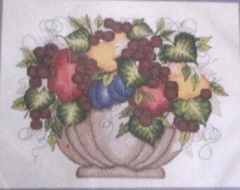 May include: A ceramic bowl filled with a variety of fruit, including apples, pears, grapes, and plums. The bowl is decorated with a floral design and sits on a white background.