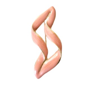 May include: A vintage brooch in a flowing, abstract design. The brooch features a twisted ribbon shape in a soft peach color with gold-colored trim. The pin is a classic accessory.