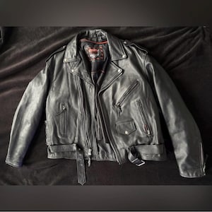 May include: Black leather motorcycle jacket with a zip fastening, multiple pockets, and a belt at the waist.