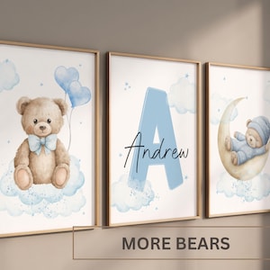 May include: Three framed watercolour prints. One shows a teddy bear with blue balloons, another a blue letter 'A' with the name 'Andrew', and the third a bear on a crescent moon. Soft pastel colours with clouds and stars.