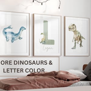Pu&ograve; includere: Tre illustrazioni ad acquerello di dinosauri incorniciate. La prima cornice mostra un plesiosauro blu. La seconda cornice mostra una lettera L verde con un piccolo dinosauro verde. La terza cornice mostra un Tyrannosaurus Rex verde. Il testo "Logan" &egrave; scritto sotto la lettera L.