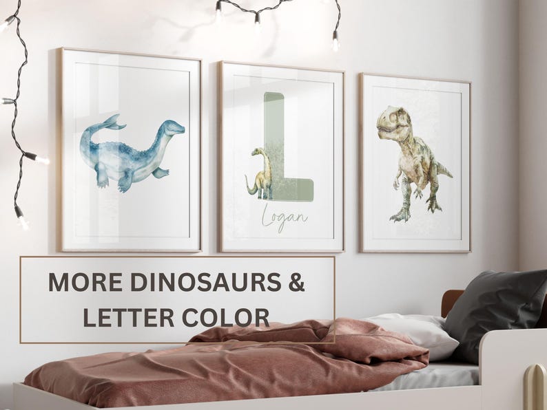 Pu&ograve; includere: Tre illustrazioni ad acquerello di dinosauri incorniciate. La prima cornice mostra un plesiosauro blu. La seconda cornice mostra una lettera L verde con un piccolo dinosauro verde. La terza cornice mostra un Tyrannosaurus Rex verde. Il testo "Logan" &egrave; scritto sotto la lettera L.