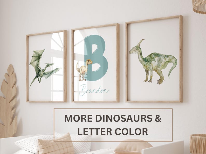 Pu&ograve; includere: Tre stampe incorniciate con illustrazioni ad acquerello di dinosauri. La stampa centrale presenta una lettera B blu e il nome Brandon. La stampa a sinistra mostra uno pterodattilo e la stampa a destra mostra un dinosauro dal collo lungo.