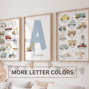 Op de afbeelding: Drie ingelijste aquarelprints. Eén toont een alfabet van voertuigen, een andere een grote blauwe letter "A" met een graafmachine en de derde, een ander alfabet van voertuigen. De tekst "MORE LETTER COLORS" staat eronder.