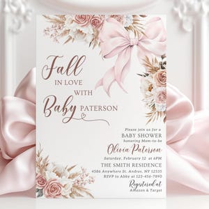 Op de afbeelding: Een uitnodiging voor een babyshower met een roze strik en bloemaccenten. De tekst luidt "Fall in Love with Baby Paterson" en bevat de evenementdetails. Geregistreerd bij Amazon & Target.