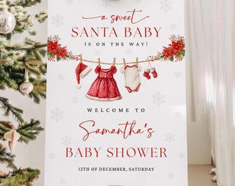 May include: A white sign on a wooden easel with the text "a sweet SANTA BABY IS ON THE WAY!" and "WELCOME TO Samantha's BABY SHOWER 12TH OF DECEMBER, SATURDAY". The sign has illustrations of baby clothes and snowflakes.