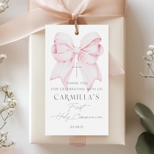 Può includere: Etichetta di ringraziamento rosa e bianca con un'illustrazione ad acquerello di un fiocco e una croce. Il testo recita "Grazie per aver celebrato con noi! La Prima Comunione di Carmilla 03.08.21"