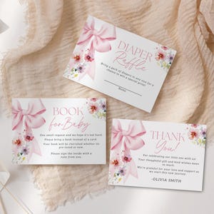 May include: Three pink and white cards with floral designs and pink bows. The first card says "DIAPER RAFFLE" and asks guests to bring a pack of diapers for a chance to win a prize. The second card says "BOOK for BABY" and asks guests to bring a book instead of a card. The third card says "THANK YOU!" and thanks guests for celebrating the new baby.