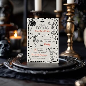 May include: A Halloween party invitation with a cream background and black and red text. The invitation features dancing skeleton illustrations, a disco ball, and bat silhouettes. The text reads "We are dying to party with you" and details the party's date, time, and location.