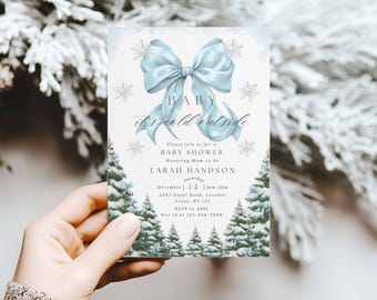 May include: A baby shower invitation with a light blue bow and snowflakes. The text "BABY it's cold outside" is displayed. The invitation includes details for the event, such as the date, time, and location.