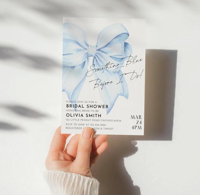 May include: A blue watercolor bow with the text "Something Blue Before I Do!" on a white background. The text below the bow reads "Please join us for a Bridal Shower honoring bride-to-be Olivia Smith 123 Little Peanut Road Chicago 60556 RSVP to Jane at 123-456-7890 Registered at Amazon & Target MAR 24 4PM".