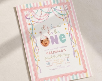 Op de afbeelding: Een rechthoekige uitnodigingskaart voor een eerste verjaardag met een pastelkleurige gestreepte rand en een geschulpte roze omlijsting. Het ontwerp bevat aquarel-stijl slingers, sterren en de tekst it's fun to be one met een babyfoto.