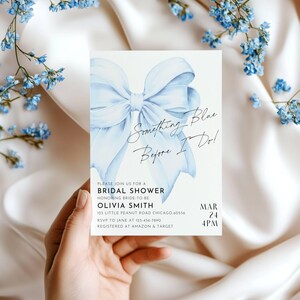 May include: A blue watercolor bow with the text "Something Blue Before I Do!" on a white background. The text below the bow reads "Please join us for a Bridal Shower honoring bride-to-be Olivia Smith 125 Little Peanut Road Chicago, 60556 RSVP to Jane at 123-456-7890 Registered at Amazon & Target Mar 24 4PM".