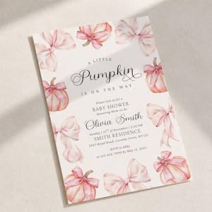 May include: A rectangular baby shower invitation card featuring watercolor illustrations of light pink pumpkins and bows. The text reads: A little Pumpkin is on the way, Please join us for a BABY SHOWER Honoring Mom-to-be Olivia Smith, Sunday 15th of November, 2:30 PM, SMITH RESIDENCE, 2563 Royal Road, Coconut Grove, NY 125, RSVP to Abby at 123-456-7890 by May 12, 2025.