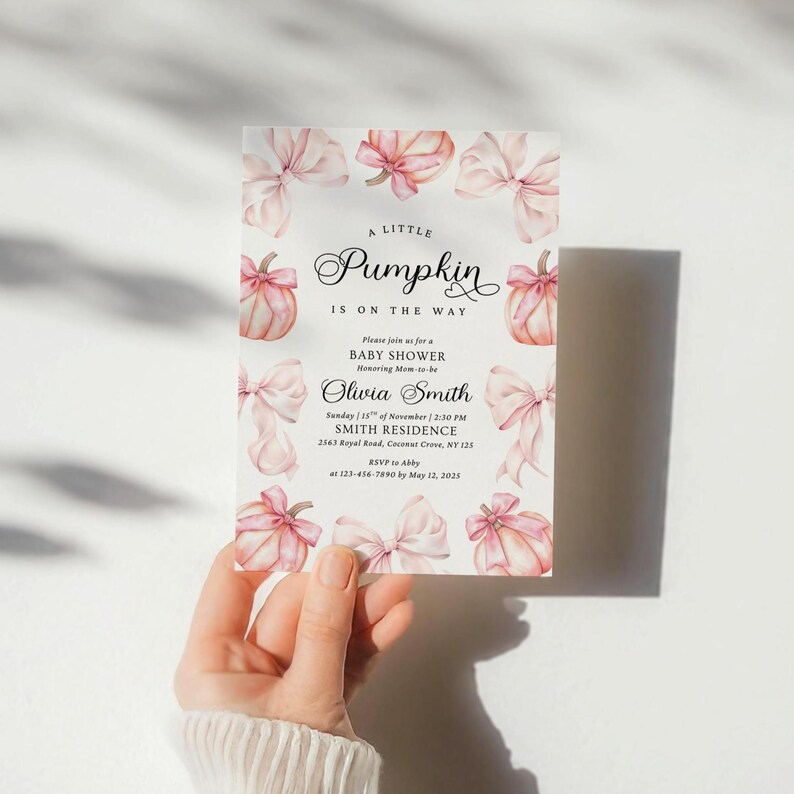 May include: A rectangular baby shower invitation card featuring a white background with watercolor illustrations of light pink pumpkins and bows along the border. The text reads A LITTLE Pumpkin IS ON THE WAY, BABY SHOWER, Olivia Smith, and details.