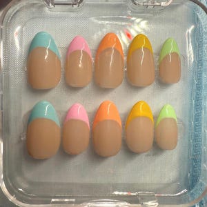 May include: Ten fake nails with a light pink, light blue, light yellow, and light green colour on the tips. The nails are oval shaped and have a natural colour base.