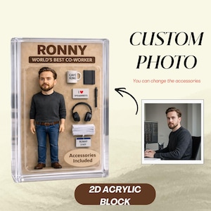 May include: A clear acrylic block featuring a miniature figure of a man, labeled "RONNY, WORLD'S BEST CO-WORKER." Accessories include a coffee mug, notebook, headphones, and the text "I ❤️ SPREADSHEETS." The block is labeled "2D ACRYLIC BLOCK."