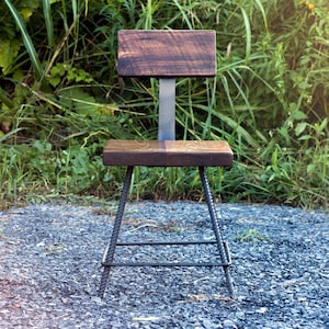 May include: A wooden chair with a dark brown stained seat and back. The chair is made with a metal frame and has a simple design.