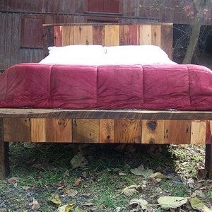 May include: A wooden bed frame with a red comforter and white pillows. The bed frame is made of reclaimed wood and has a rustic look.