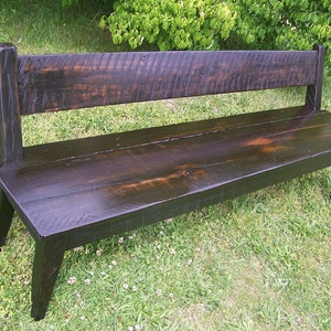 May include: A dark brown wooden bench with a simple design. The bench has a back and is made of reclaimed wood.