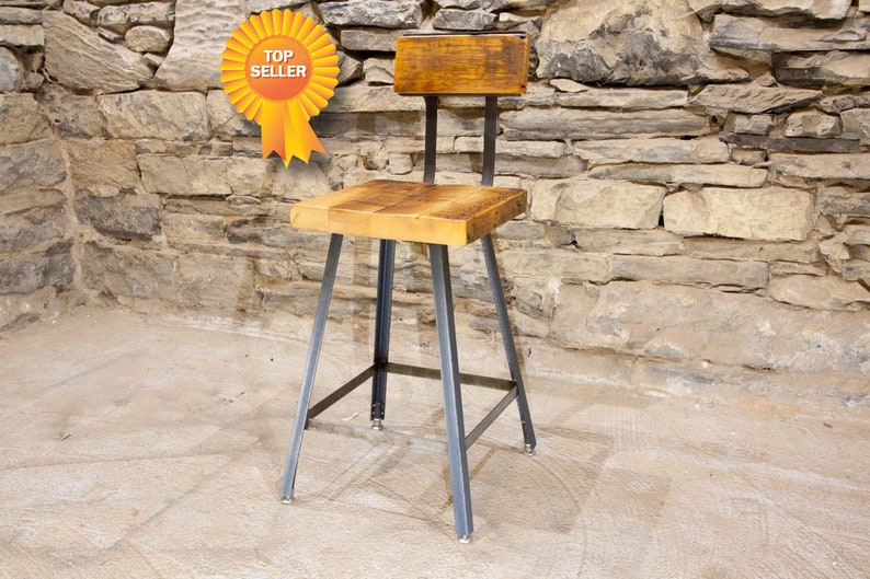 May include: A rustic wooden bar stool with a metal frame. The seat and back are made of reclaimed wood and the frame is black metal. The stool is standing on a light gray stone floor.