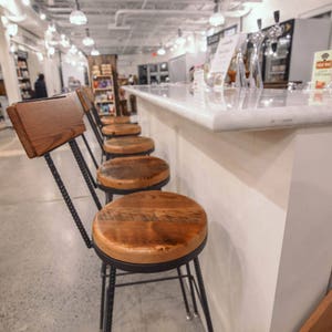 Bar stools with wooden back and top and black metal legs in a big venue