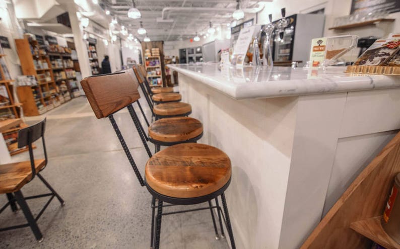 Bar stools with wooden back and top and black metal legs in a big venue