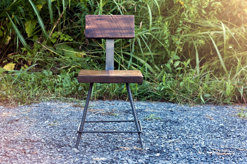 May include: A wooden chair with a dark brown stained seat and back. The chair is made with a metal frame and has a simple design.