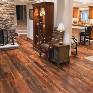 May include: A living room with a rustic aesthetic, featuring a stone fireplace, hardwood floors, and a wooden display cabinet. The room is illuminated by a lamp and natural light, creating a warm and inviting atmosphere.