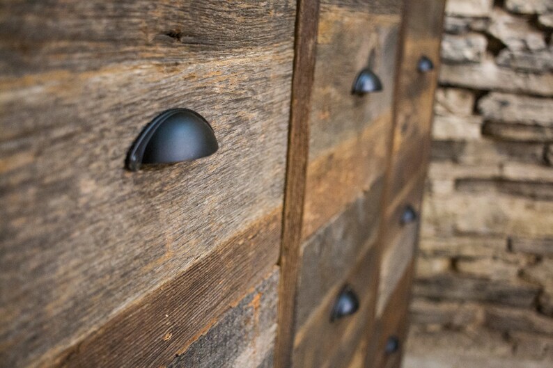 May include: A rustic wooden dresser with black metal drawer pulls. The dresser is made of reclaimed wood and has a natural, weathered finish.