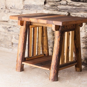 May include: A rustic wooden table with a natural wood finish. The table has a rectangular top and a simple, sturdy design. The table is made of reclaimed wood and has a unique, handcrafted look.