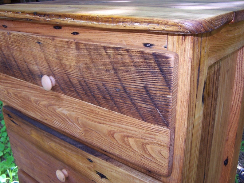 May include: A wooden dresser with three drawers and a light brown stain. The drawers have simple wooden knobs. The dresser is made of reclaimed wood with a rustic look.