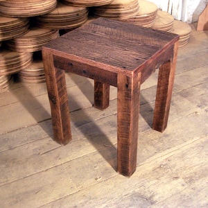 May include: A rustic wooden end table with a square top and four legs. The table is made of reclaimed wood and has a natural, weathered finish.