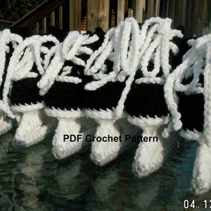 May include: A set of six crocheted black and white ice skate ornaments. The skates have white laces and are tied with a bow. The text "PDF Crochet Pattern" is visible in the image.