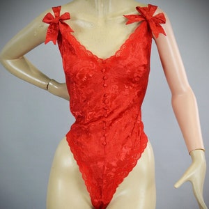 May include: Red lace bodysuit with a button-up front and bow details on the straps.