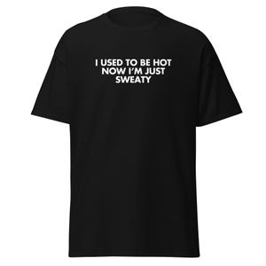 Könnte beinhalten: Schwarzes T-Shirt mit dem weißen Text "I USED TO BE HOT NOW I'M JUST SWEATY". Das kurzärmelige Shirt ist aus weichem Material und hat einen Rundhalsausschnitt. Der Text ist mittig auf der Vorderseite des Shirts platziert.