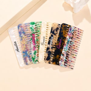 May include: A collection of seven rectangular hair combs featuring various patterns including white, multicolored, green, cream, tortoiseshell, and confetti designs. Each comb is personalized with a name in script or print font.