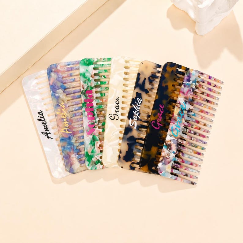 May include: A collection of seven rectangular hair combs featuring various patterns including white, multicolored, green, cream, tortoiseshell, and confetti designs. Each comb is personalized with a name in script or print font.