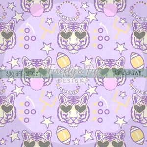 May include: A repeating pattern on a light purple background featuring tiger faces with heart-shaped sunglasses, American footballs, stars, and the word "GEAUX" in a necklace. The design also includes a football play diagram and the text "Firefly & Fig Designs".