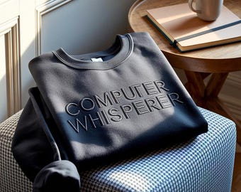Op de afbeelding: Een donker antracietgrijze sweater met ronde hals en de tekst "COMPUTER WHISPERER" geborduurd in een bijpassende draadkleur op de borst. Het kledingstuk heeft lange mouwen en een geribbelde halslijn, wat zorgt voor een strak ontwerp.