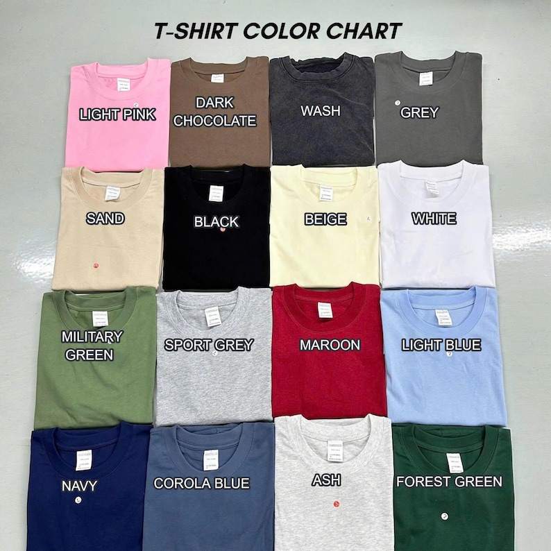 May include: A T-SHIRT COLOUR CHART displaying fifteen folded crew neck t-shirts in various colours including light pink, dark chocolate, wash, grey, sand, black, beige, white, military green, sport grey, maroon, light blue, navy, corola blue, and ash.
