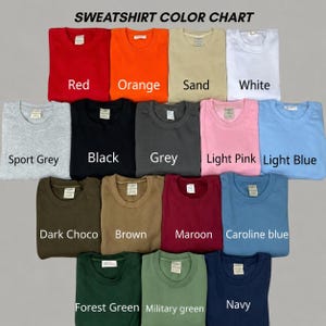 May include: A sweatshirt color chart featuring seventeen folded crewneck sweatshirts in various colors including red, orange, sand, white, sport grey, black, grey, light pink, light blue, dark choco, brown, maroon, caroline blue, forest green, military green, and navy.