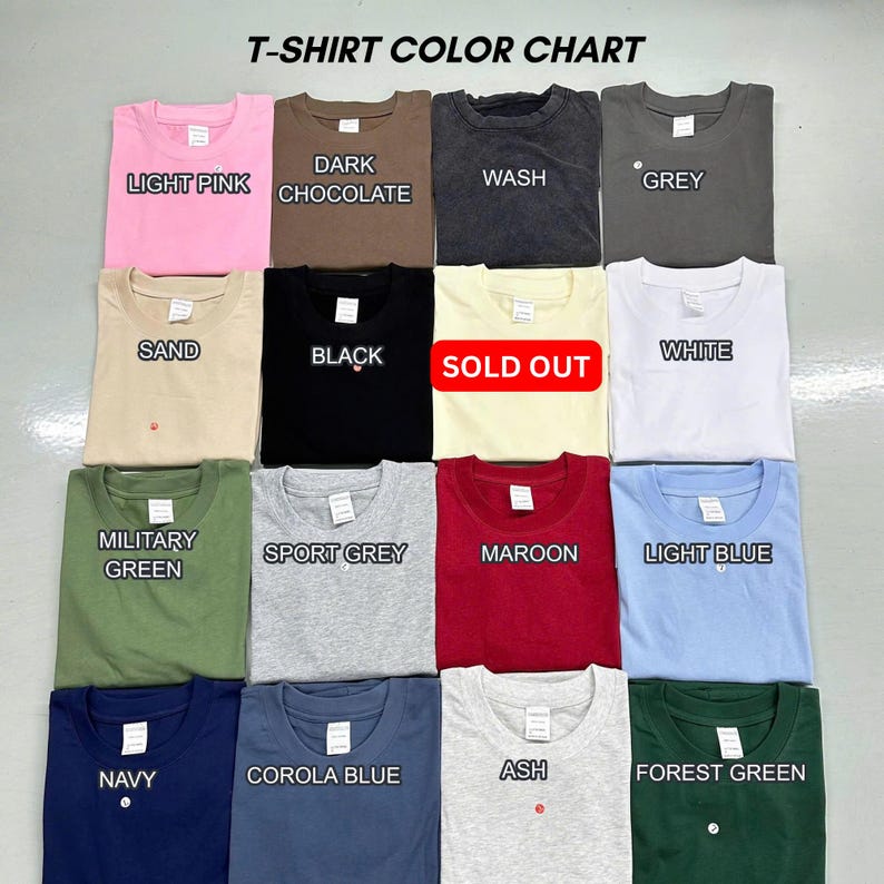 May include: A T-shirt color chart displaying sixteen folded shirts in various colors including light pink, dark chocolate, wash, grey, sand, black, white, military green, sport grey, maroon, light blue, navy, corola blue, ash, and forest green.