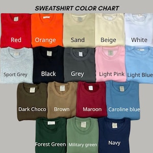 May include: A sweatshirt color chart displaying fifteen folded crewneck sweatshirts in various colors including red, orange, sand, beige, white, sport grey, black, grey, light pink, light blue, dark choco, brown, maroon, caroline blue, forest green, military green, and navy.