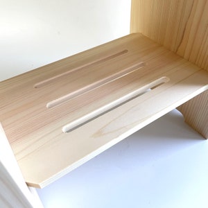 Minimalist Japanese hinoki wood bath stool with a slatted shelf, crafted for durability and traditional spa-style elegance.